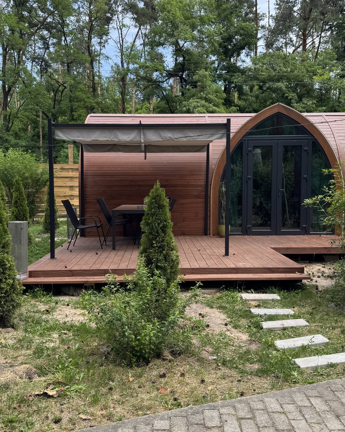 Два збудовані модулі GoodWoodHome зі спільною терасою під перголою в сосновому лісі